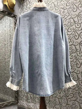 Light blue denim shirt with white lace trim on a patterned wall background